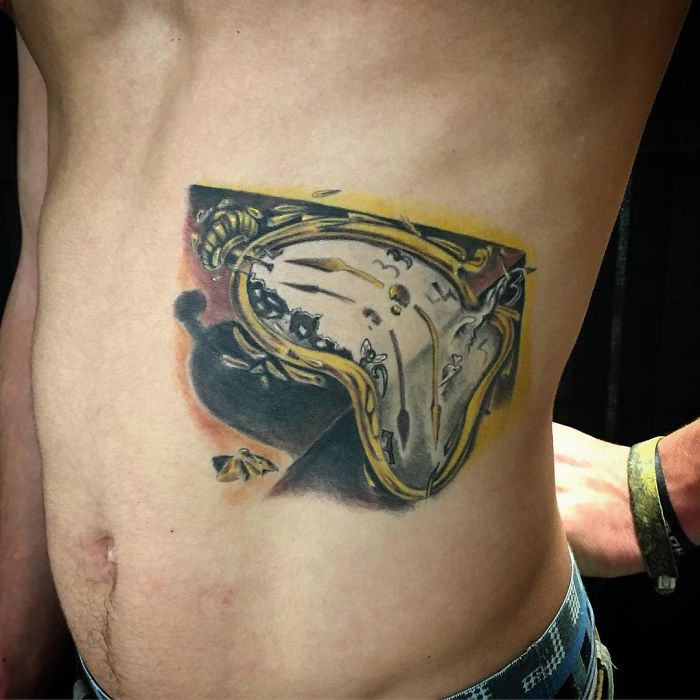 Classical art-inspired tattoo of a melting clock on a person's side.