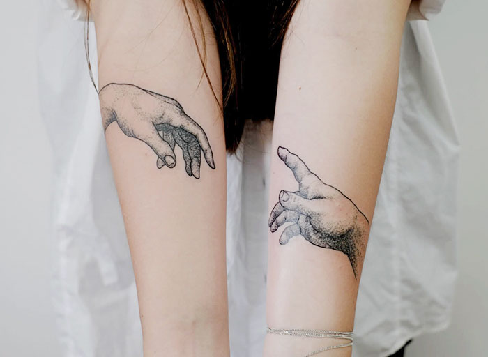 Two forearm tattoos depicting hands inspired by classical art.