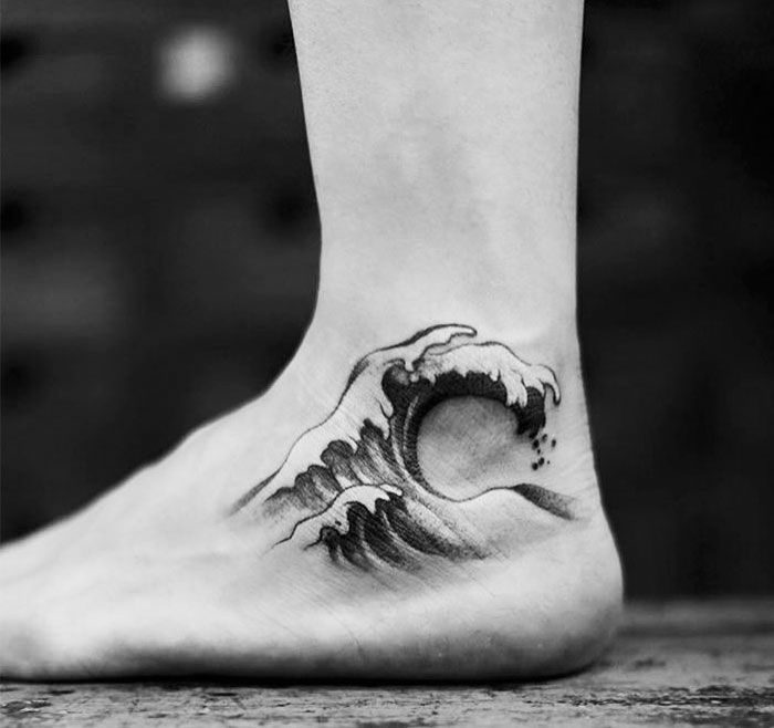 Elegant classical art-inspired wave tattoo on foot, showcasing intricate design and fine details.