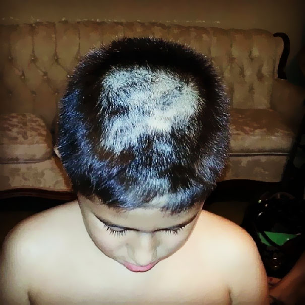 Child with uneven haircut looking down, showcasing a self-given haircut mishap.