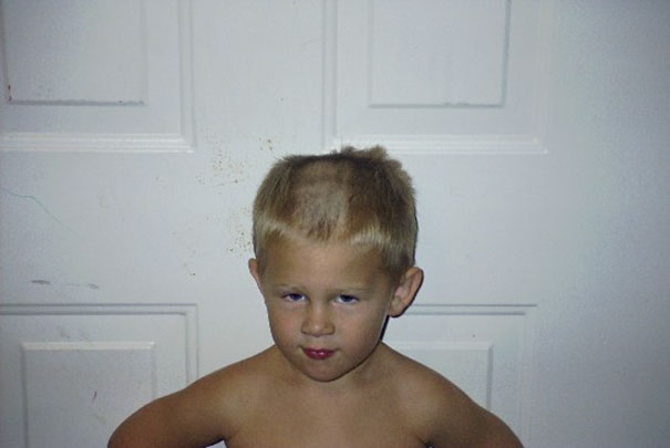 Child with an uneven self-inflicted haircut standing in front of a white door, looking regretful.