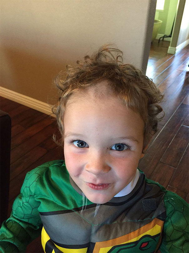 A child with a self-inflicted uneven haircut, looking amused in a colorful costume.
