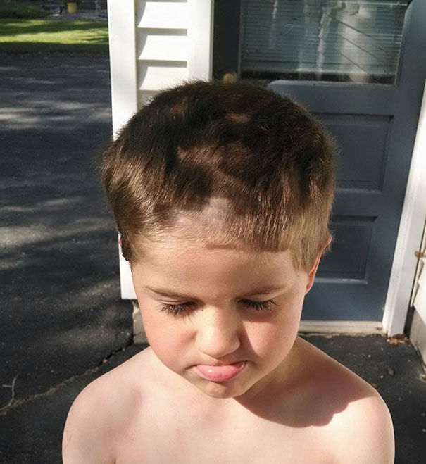 Child with uneven haircut, looking regretful after self hair-cutting attempt.