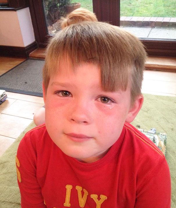 Child with uneven haircut looking regretful after cutting own hair at home.