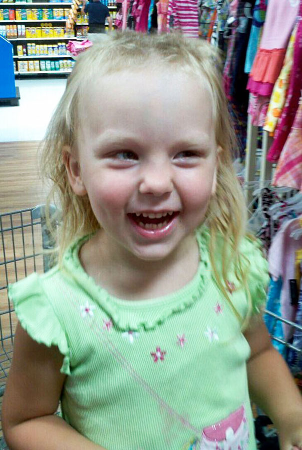 Young kid with a playful haircut, smiling in a store, showing self-cut hair adventure.