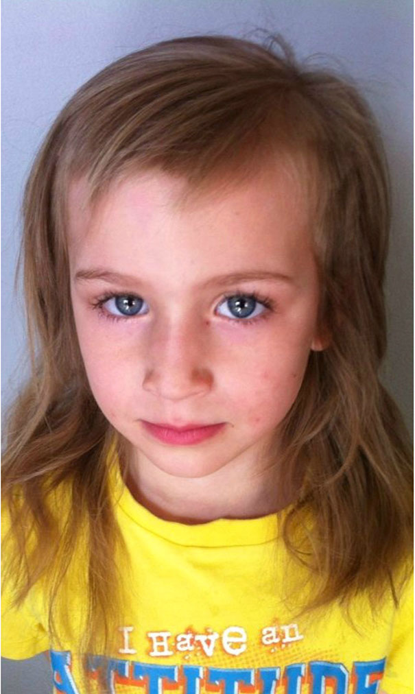 Child with a self-cut hairstyle, wearing a yellow shirt, looking slightly regretful.