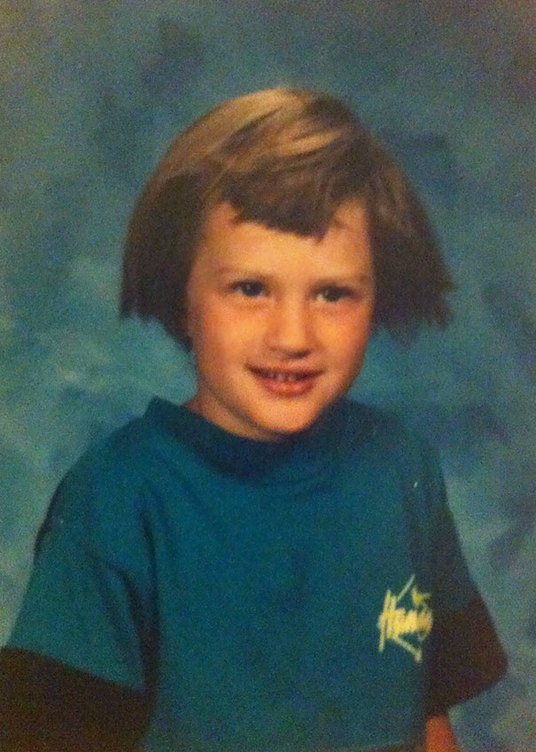 A young child with self-cut hair in a school portrait, wearing a blue shirt.
