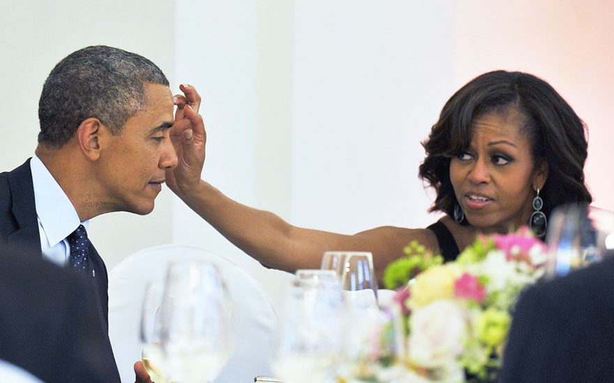 Michelle removing something from Baracks' forehead
