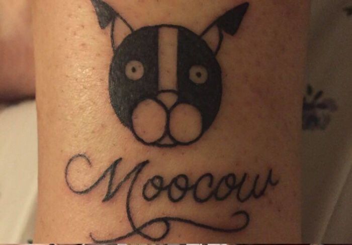 Minimalist dog tattoo with 'Moocow' text on skin.