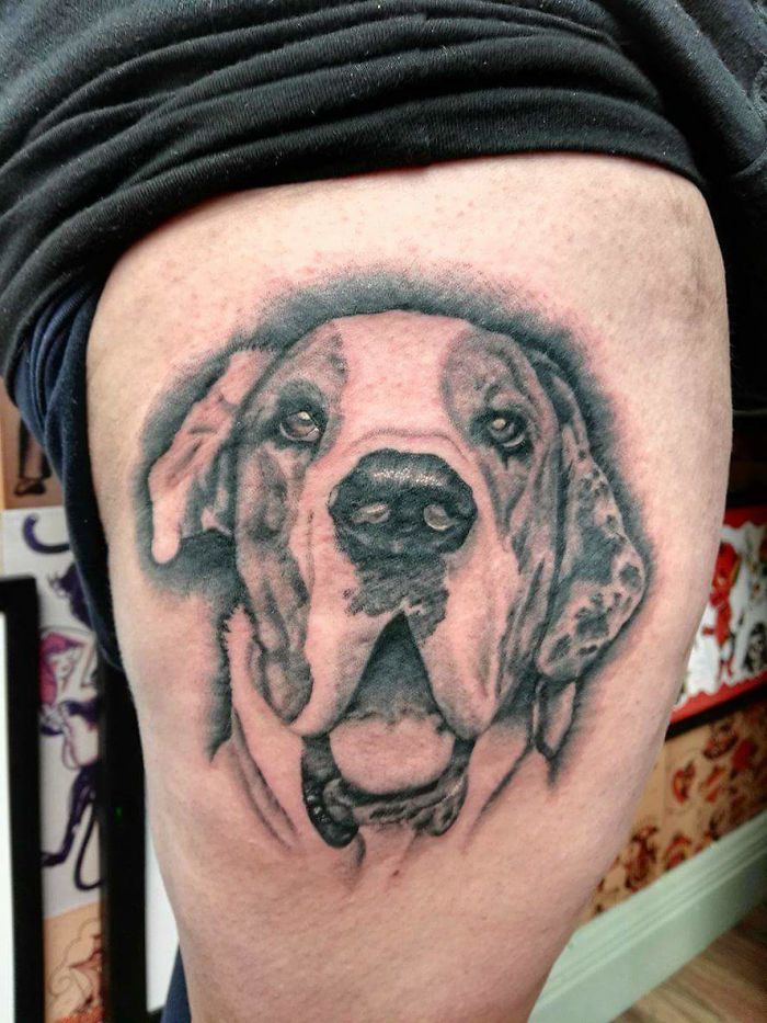 Dog tattoo design on upper thigh, featuring a detailed canine face in black and gray tones.