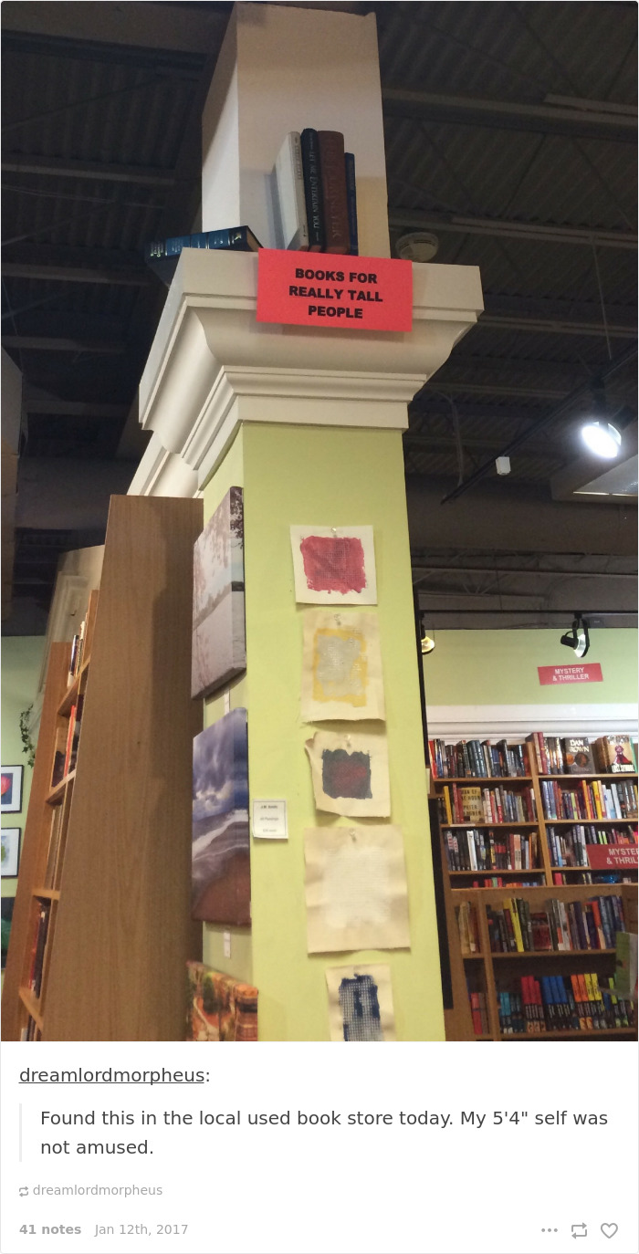 Books labeled "for really tall people" placed on a high shelf, highlighting short people problems in a bookstore.