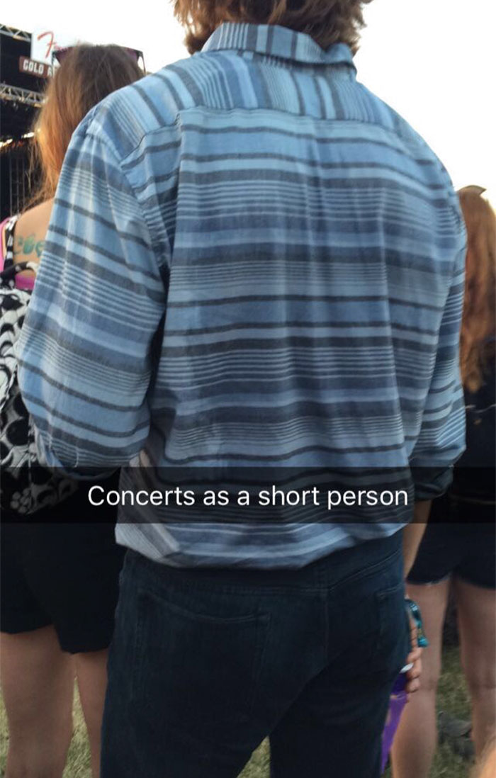 Short person at a concert, struggling to see over taller attendees, highlighting common problems faced by short people.