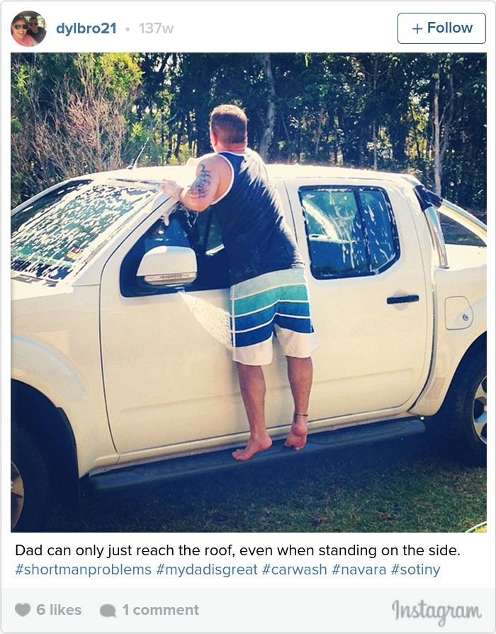 Man standing on truck's side to reach roof, illustrating short people problems during a car wash.