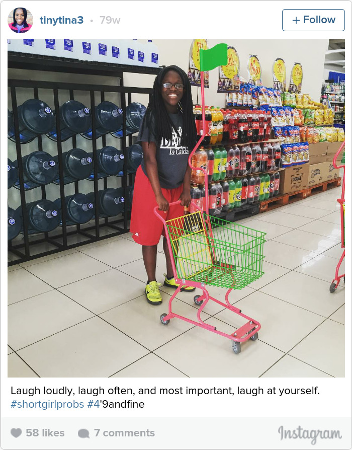 Person smiling near a small shopping cart in a store aisle, representing short people problems humor.