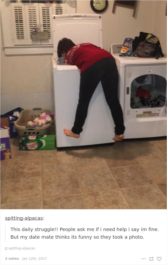 Person struggles to reach inside a washing machine, humorously highlighting short people problems.