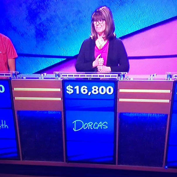 Contestant with a funny name "Dorcas" on a game show, standing behind a podium with $16,800 displayed.