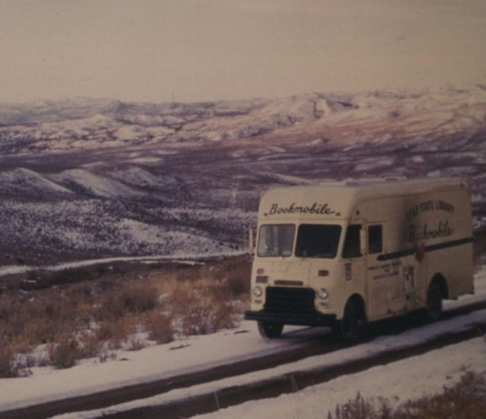 Vintage bookmobile driving through snowy rural landscape, showcasing libraries-on-wheels bringing books to remote areas.