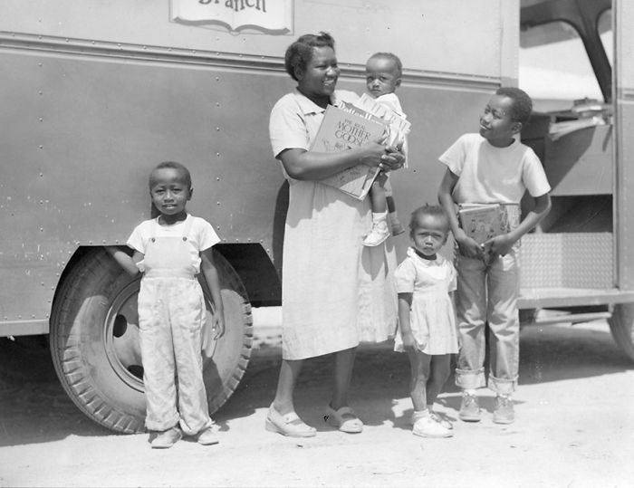 Mother and children standing outside a bookmobile, holding books in this rare library on wheels photo.
