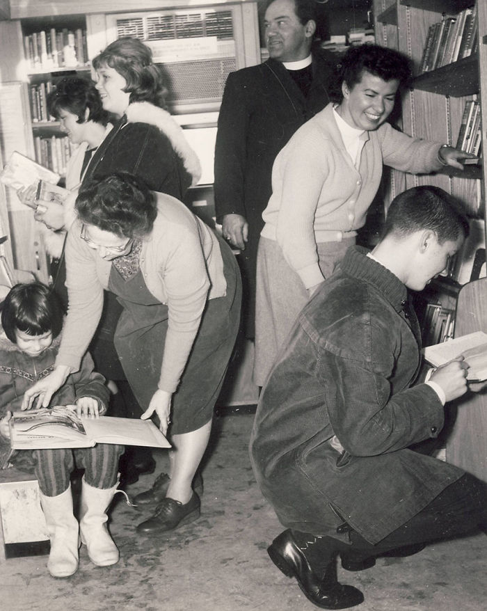 Children and adults browsing books inside a vintage bookmobile, showcasing libraries-on-wheels from the past.
