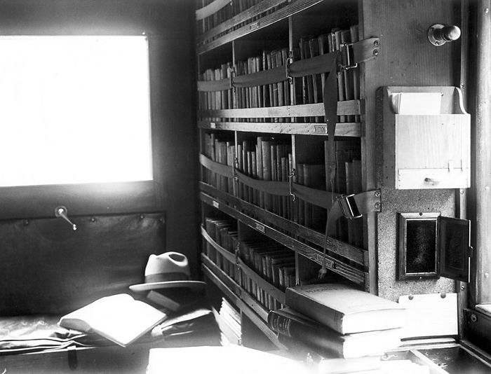 Interior of a vintage bookmobile showing shelves filled with books and an open book on a seat inside the mobile library.