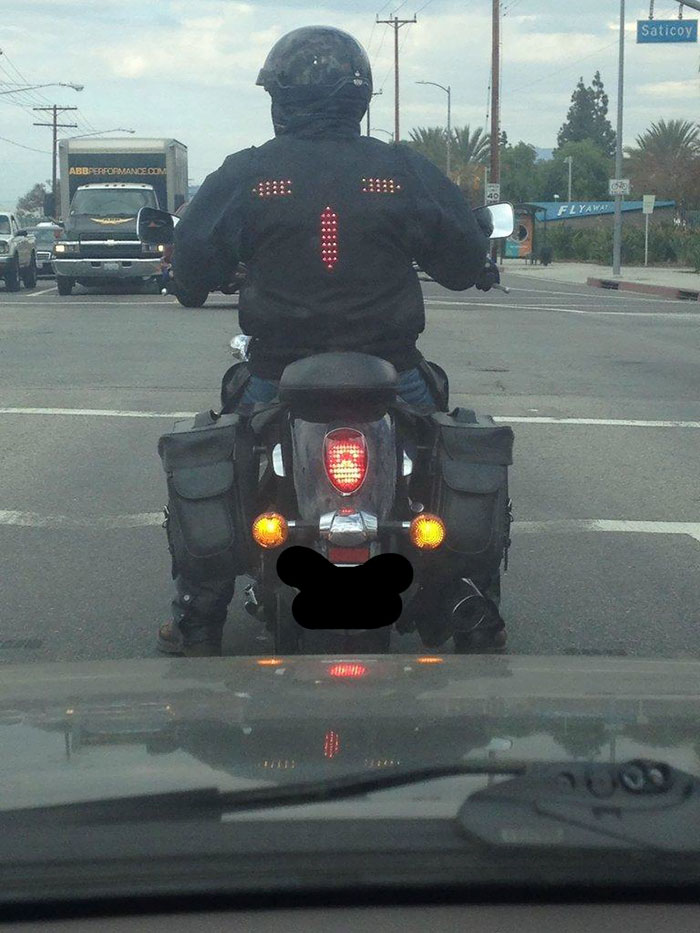 the biker on the motorcycle wearing the jacket with signal and brake lights