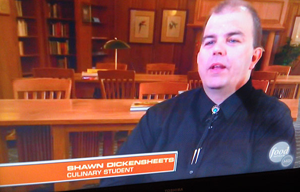 Culinary student featured in a TV program, highlighting a funny name on screen in a library setting.