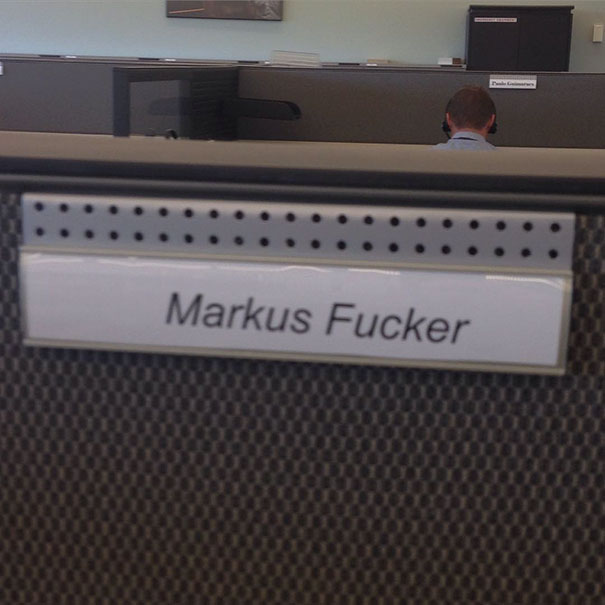 Funny nameplate with humorous name in an office cubicle setting.