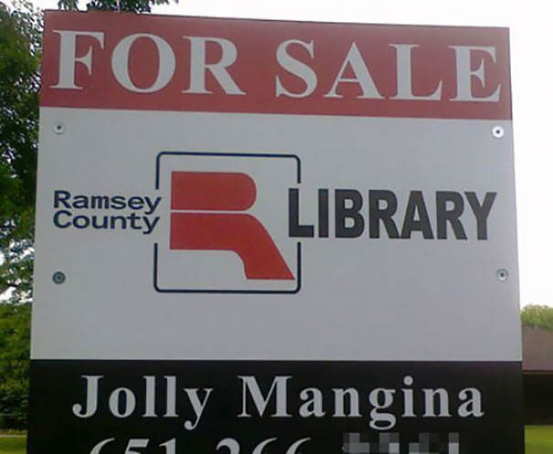 "For sale sign outside Ramsey County Library with a funny name below."