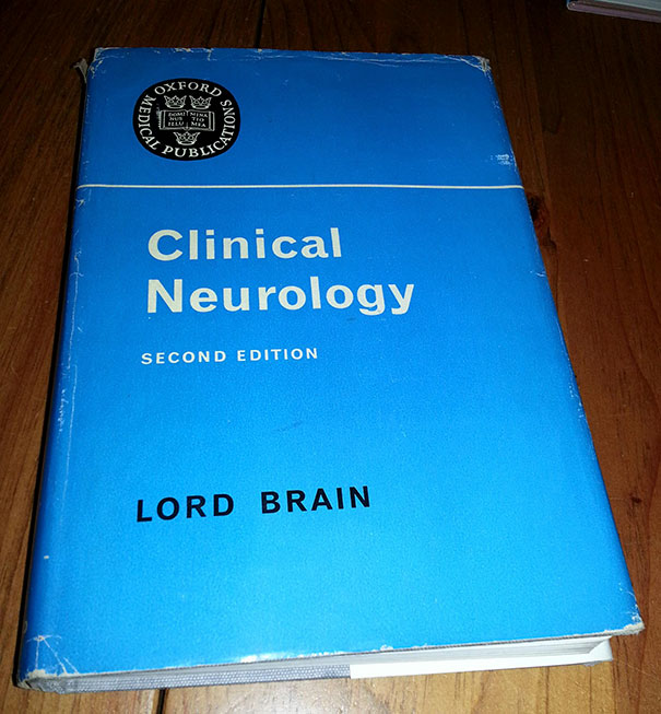 Book titled "Clinical Neurology" by Lord Brain, an example of funny names, with a blue cover on a wooden table.