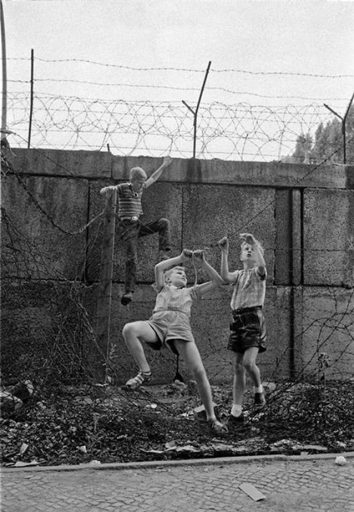 Children Playing At The Berlin Wall Near Bernauer Strasse. The Three Boys Are Climbing Up The Wall And Moving Along A Barbed Wire Fence Alongside The Wall Hand By Hand, 1963