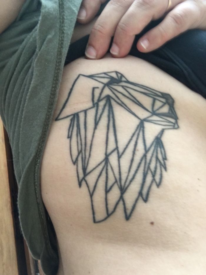 Geometric dog tattoo design on a person's ribcage.