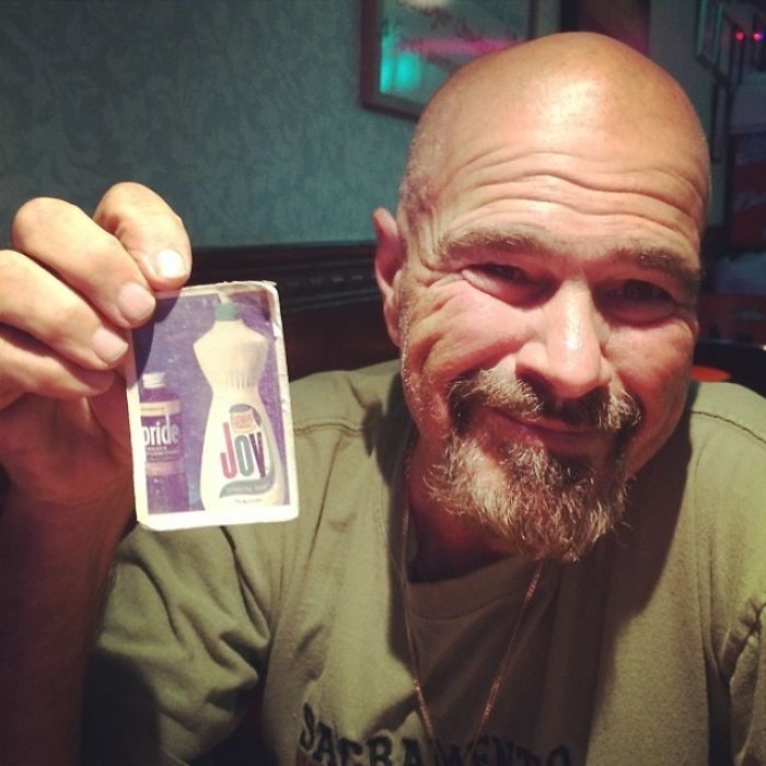 Bald dad holding a card with dish soap, demonstrating his humor in a playful setting.
