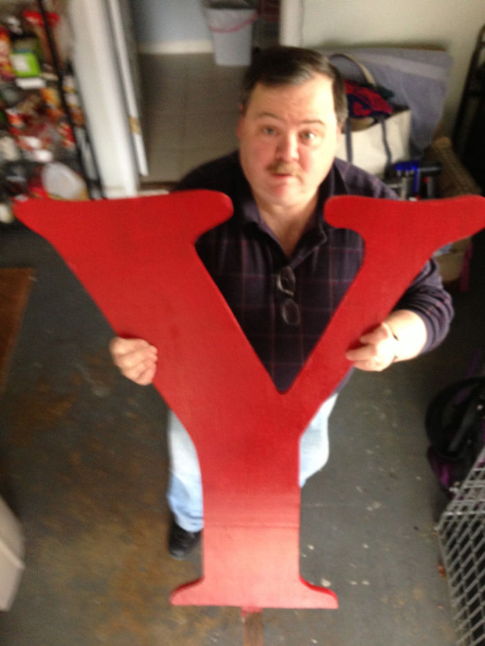 Dad humor elevated with a large red letter Y prop indoors.