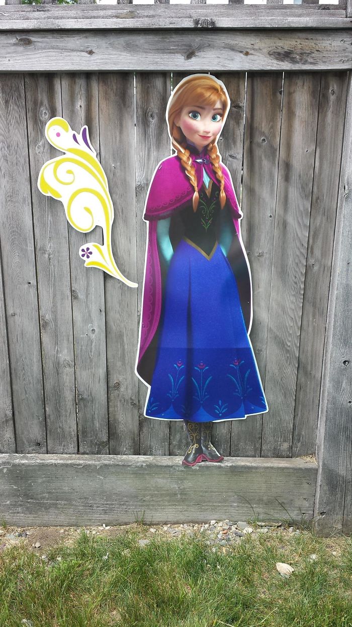 Cardboard cutout of an animated character humorously placed on a wooden fence, showcasing dad-level jokes.