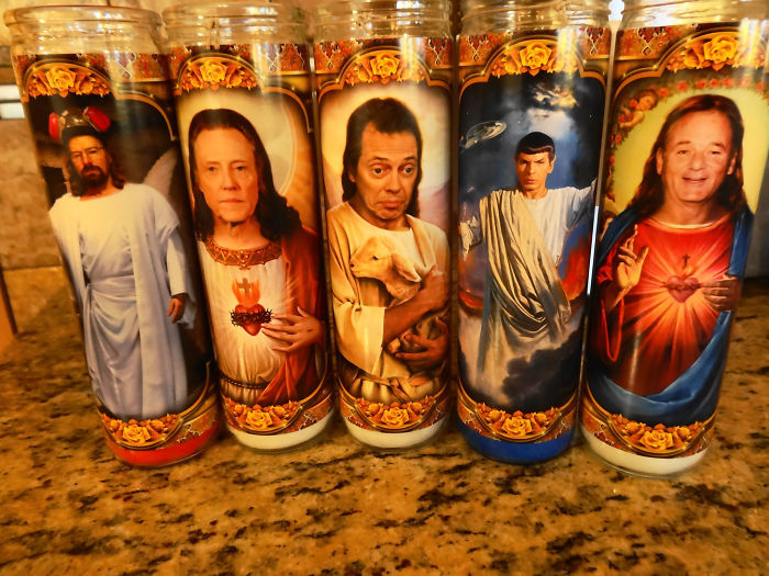 Dads' jokes taken to another level with humorous saint-themed candles on a countertop.