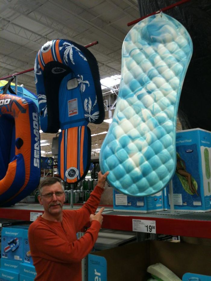 Man humorously pointing at a pool float resembling a sanitary pad, showcasing dad jokes taken to another level.