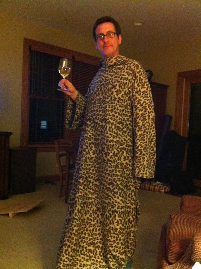 Dad humor in action: wearing a leopard print snuggie while holding a wine glass, showcasing playful fashion.