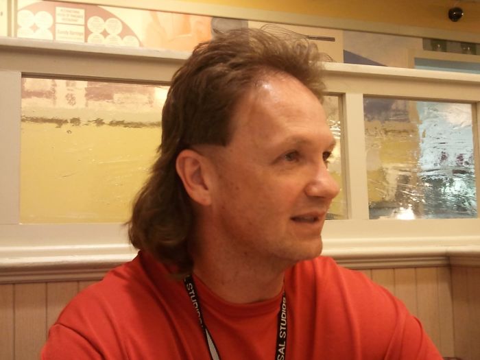 Dad with a mullet hairstyle in a restaurant, showcasing his sense of humor and style.