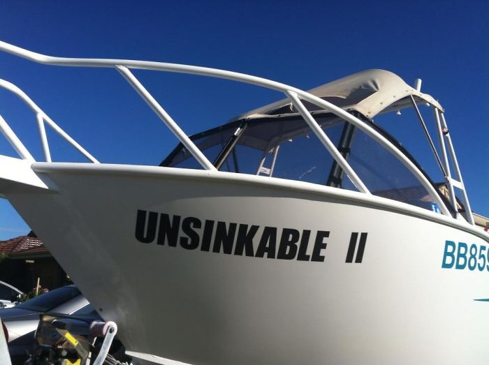 Boat named "Unsinkable II," showcasing dad humor with a clever joke, against a clear blue sky.