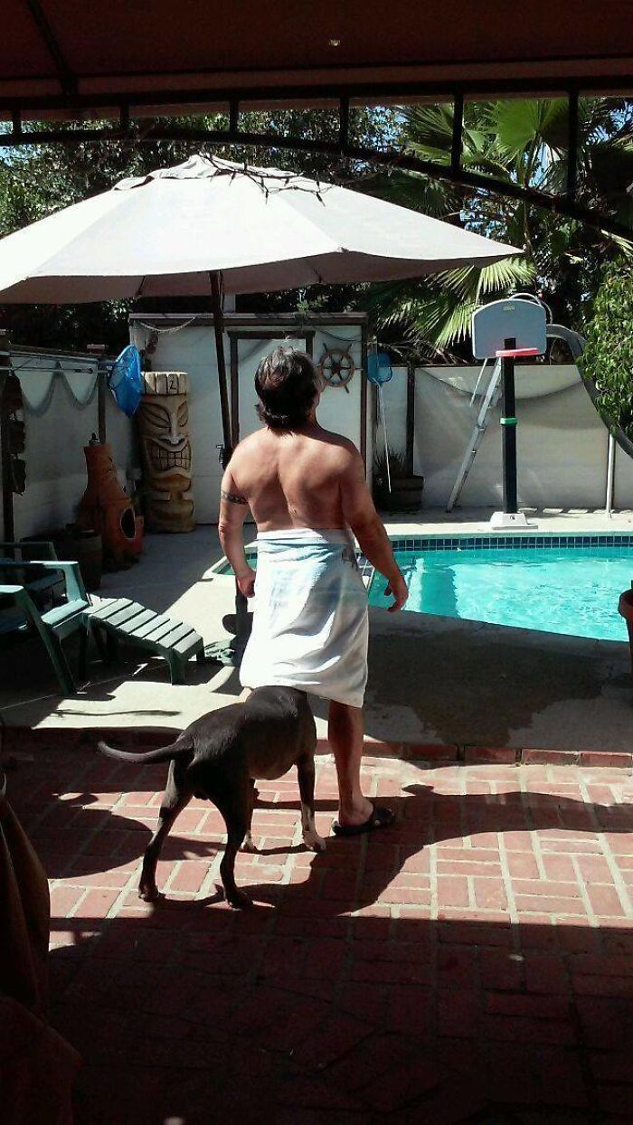 Dad by the pool in a towel with a dog, showcasing elevated dad jokes.