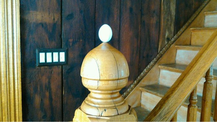 Egg placed on a wooden stair banister, showcasing a dad's joke taken to another level.