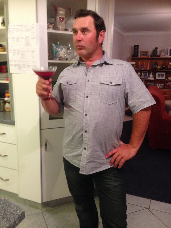 A dad humorously poised with a cocktail in a kitchen, showcasing funny dad jokes.