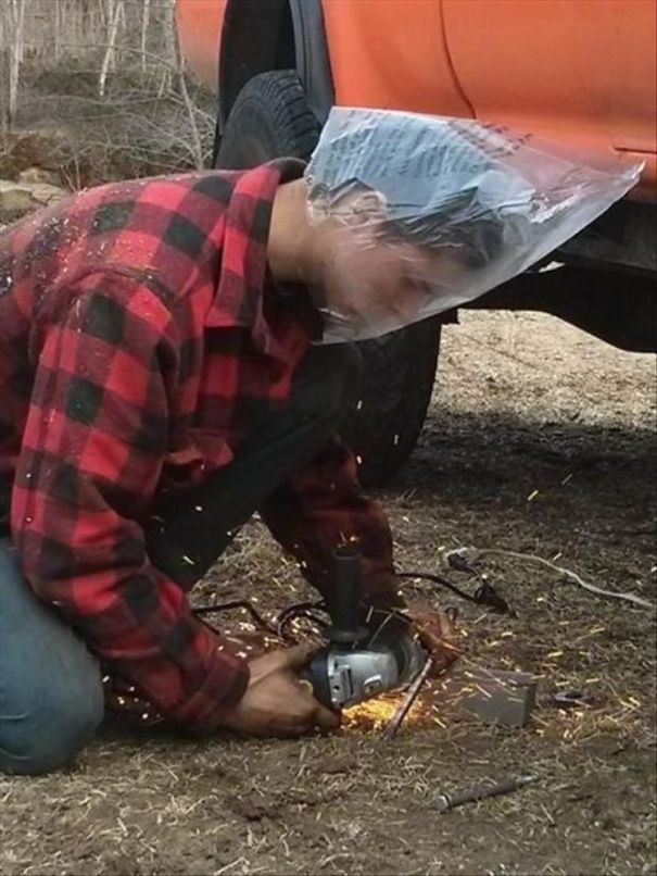 Man in plaid shirt using angle grinder with plastic bag on head, illustrating why women live longer than men.