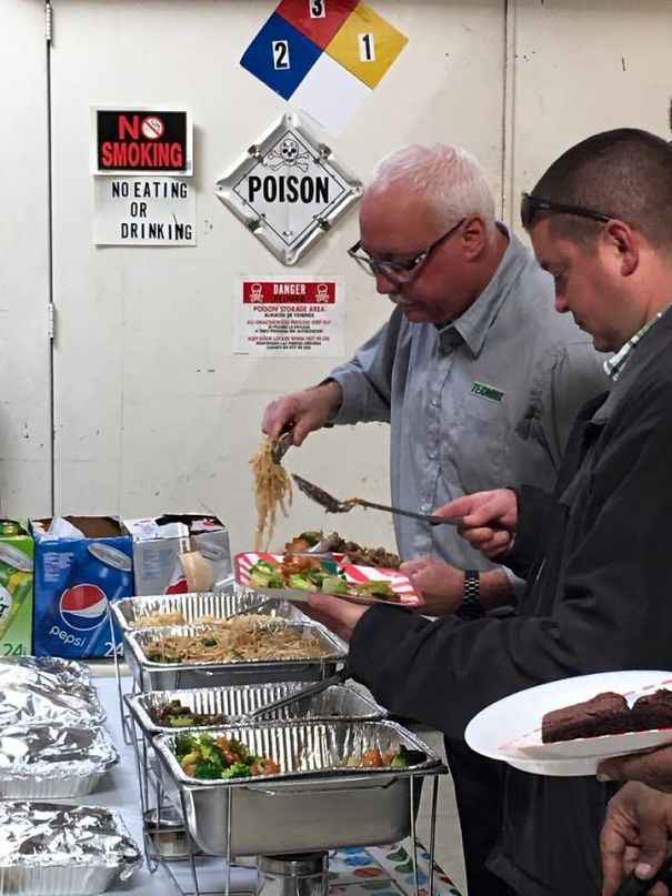Two men serving food from trays beneath a "No Eating or Drinking" and "Poison" sign, highlighting why women live longer.