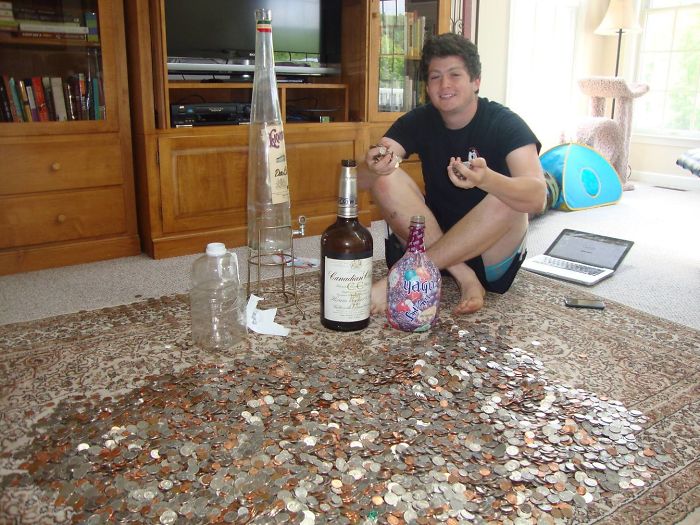 Man surrounded by bottles and coins, playfully demonstrating a dad joke taken to another level.