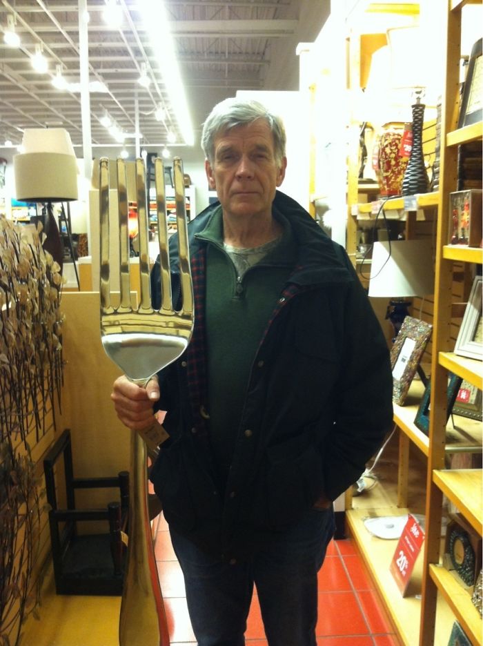 Man holding a giant fork in a store, illustrating dads taking jokes to another level.