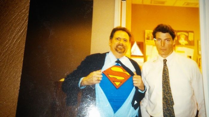 Dad reveals Superman shirt under suit, making a playful joke.