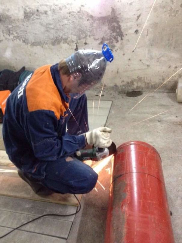 Man using bottle as face shield, grinding a metal pipe, sparks flying. Illustrates why women live longer than men.