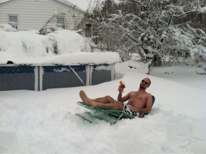 Dad reclining on a lounge chair in a snow-covered yard, holding a drink, showcasing dad jokes at another level.