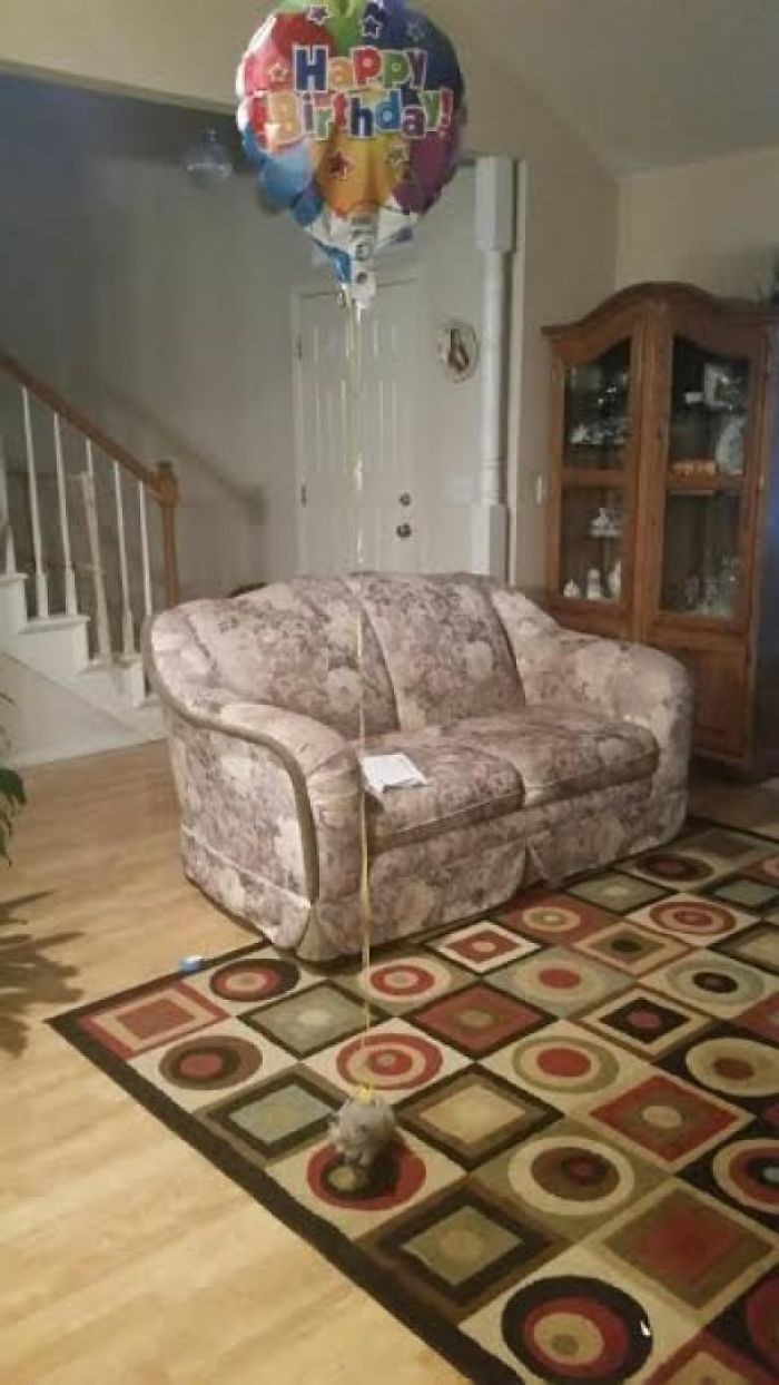 Dad's joke: birthday balloon tied to a small rock on a patterned rug in a living room.